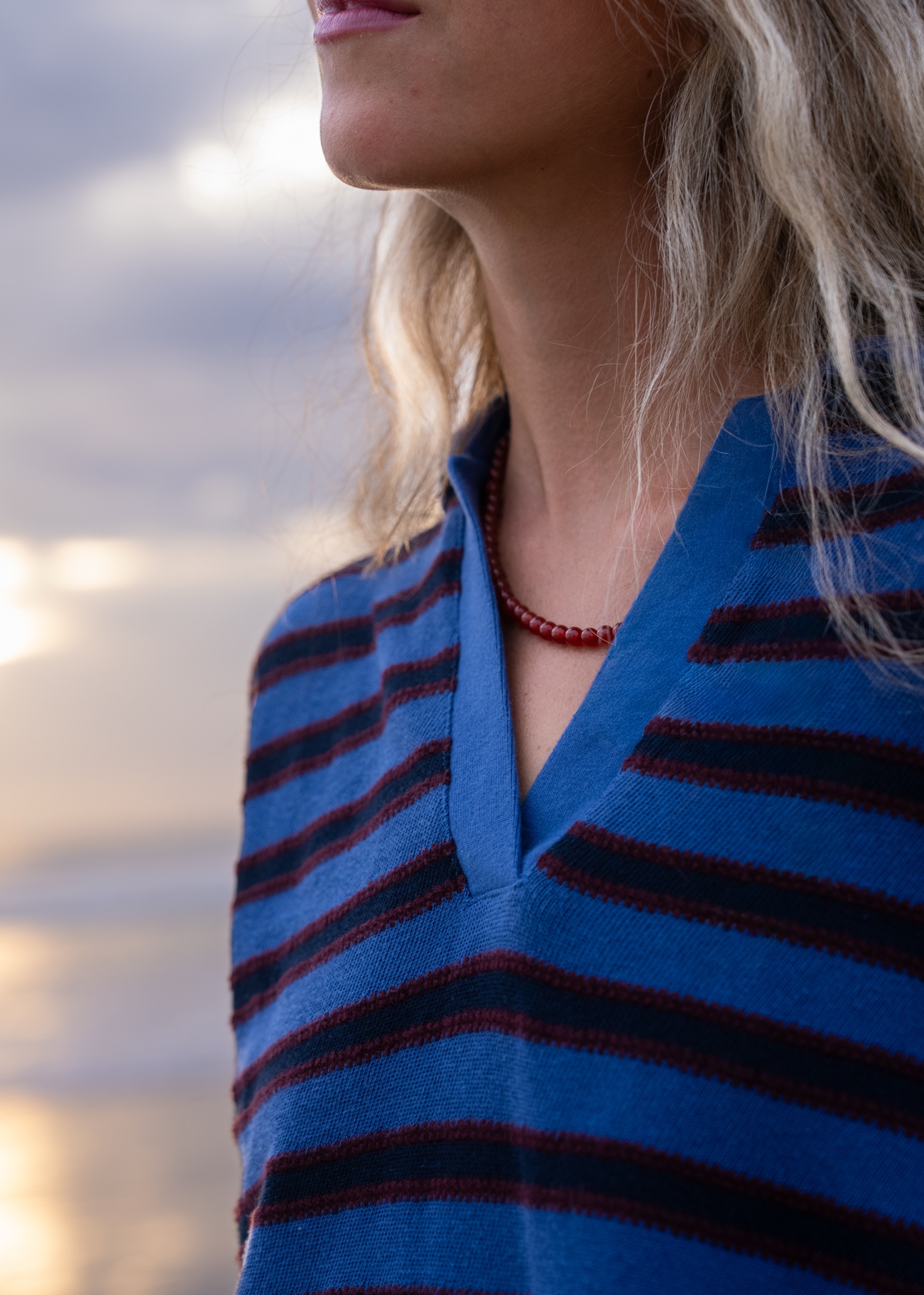 A woman in a blue striped top wearing an Almara necklace