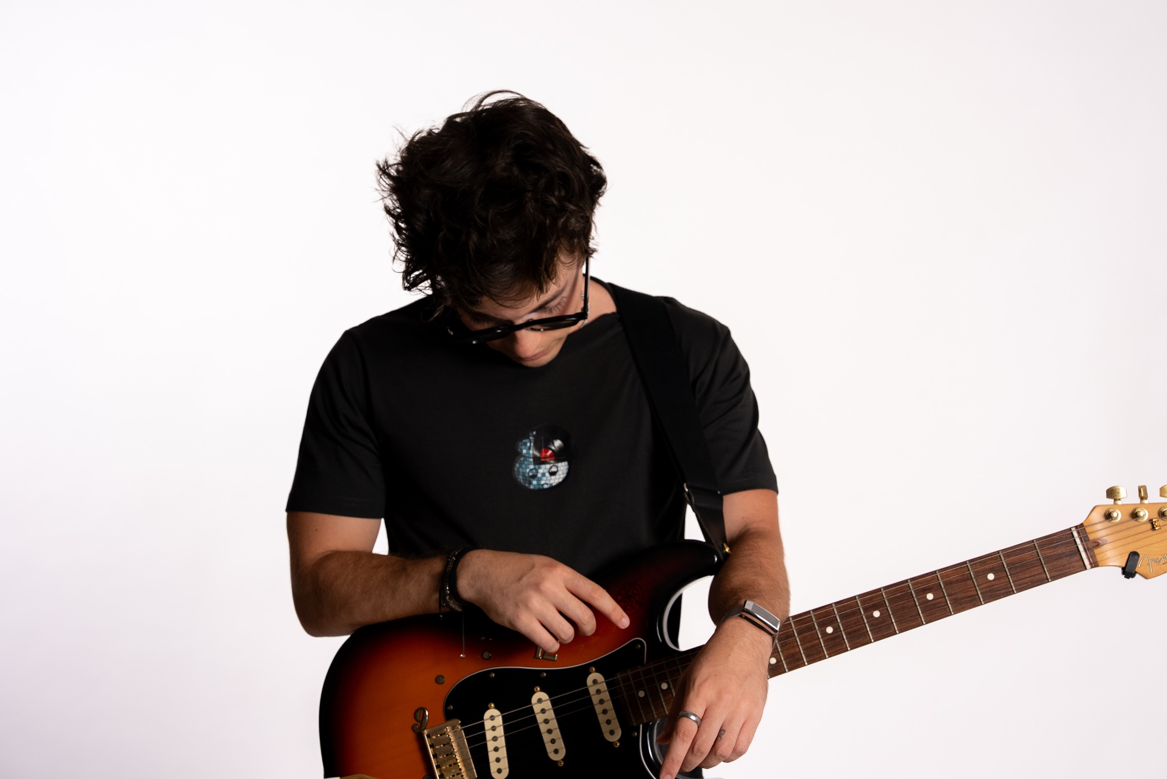 A man in a black Boys Don't Cry tee holding an electric guitar